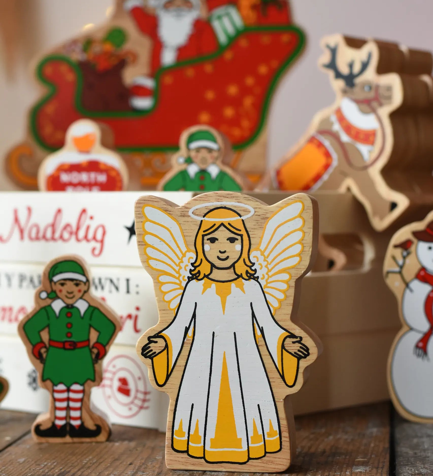 Lanka Kade Christmas angel toy in yellow and white next to a Christmas eve box filled with Lanka Kade figures.