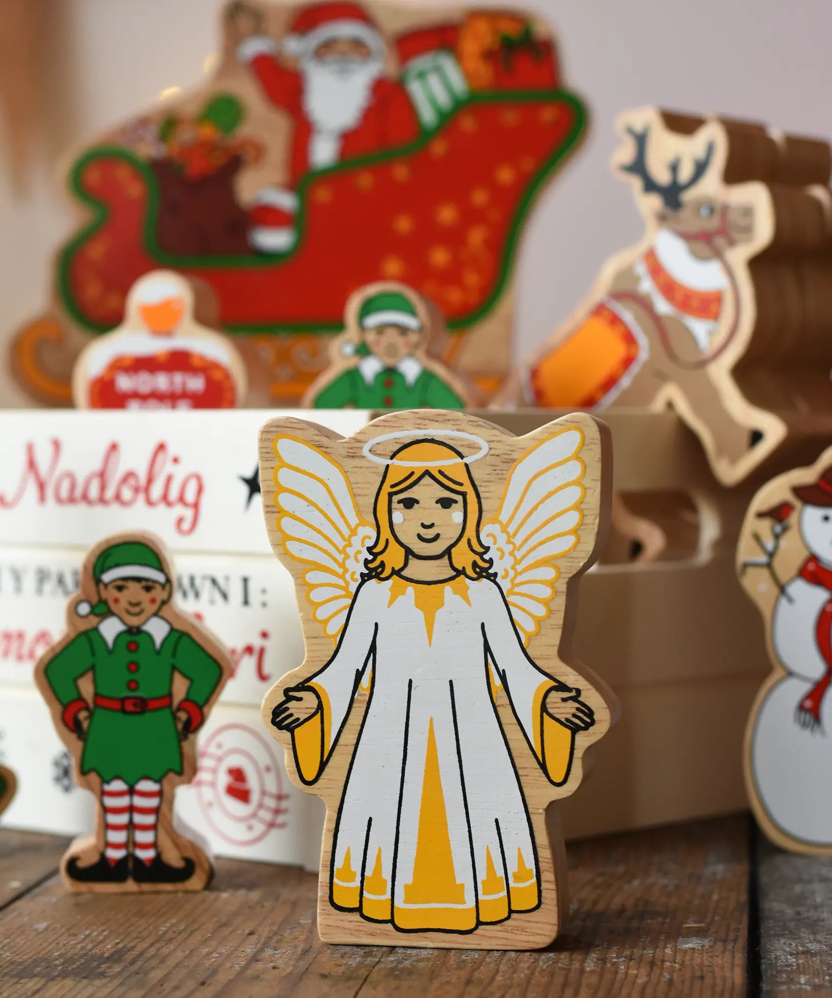 Lanka Kade Christmas angel toy in yellow and white next to a Christmas eve box filled with Lanka Kade figures.