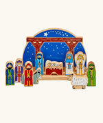 Lanka Kade wooden Nativity scene toy set featuring colorful painted wooden figures of animals and biblical characters, arranged in front of a wooden stable.