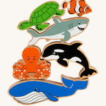 Lanka Kade Wooden Sealife Animals Bag of 6, are fun marine life figures and include a whale, an octopus, an orca, a shark, a turtle and a clown fish, all with happy and smiling faces. The image is on a cream background
