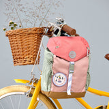 Lassig kids mini outdoor backpack in sunny explorer pink hanging on a yellow bicycle. 