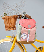 Lassig kids mini outdoor backpack in sunny explorer pink hanging on a yellow bicycle. 
