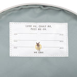 The inside of the Lassig kids tiny Dino backpack, showing the name label that has multiple spaces for when the bag is passed on to younger kids. 