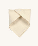 The Lassig organic cotton muslin bandana dribble bib, in a creamy Vanilla colour, with little push-in metal fastenings at the neck.