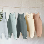 5 different coloured Lassig organic cotton muslin jumpsuits, hanging on a string of twine. 