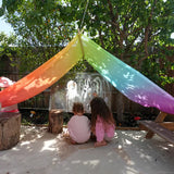 Laura's play cotton large bright rainbow play cloths in bright rainbow as a shelter with children playing underneath