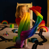 Child playing with Laura's play cotton large bright rainbow play cloths in a playroom 