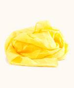 Bright yellow 100% organic cotton play cloth ruffled up into a pile