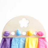 Laura's play cotton purple, blue yellow and pink organic cotton cloths on a wooden display.
