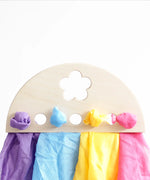 Laura's play cotton purple, blue yellow and pink organic cotton cloths on a wooden display.