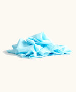 Lauras play cotton play cloth in light blue, made from 100% organic cotton, 90cm square, ruffled up into a pile.