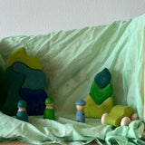 Light green organic cotton play cloth used as a backdrop for different wooden figures stackers and a car