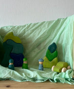Light green organic cotton play cloth used as a backdrop for different wooden figures stackers and a car
