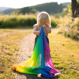 Child holding a Laura's play cotton rainbow cloth made from organic cotton in a grassy field