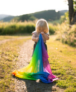 Child holding a Laura's play cotton rainbow cloth made from organic cotton in a grassy field