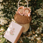 Olli Ella Limited Edition Blossom Buds Gift Set - Tulip showing Dozy Dinkum - Talia Tulip & Dinky Dinkum Doll - Tessa Tulip sat inside an Olli Ella basket on a flowery setting, with the packaging box lent against the basket
