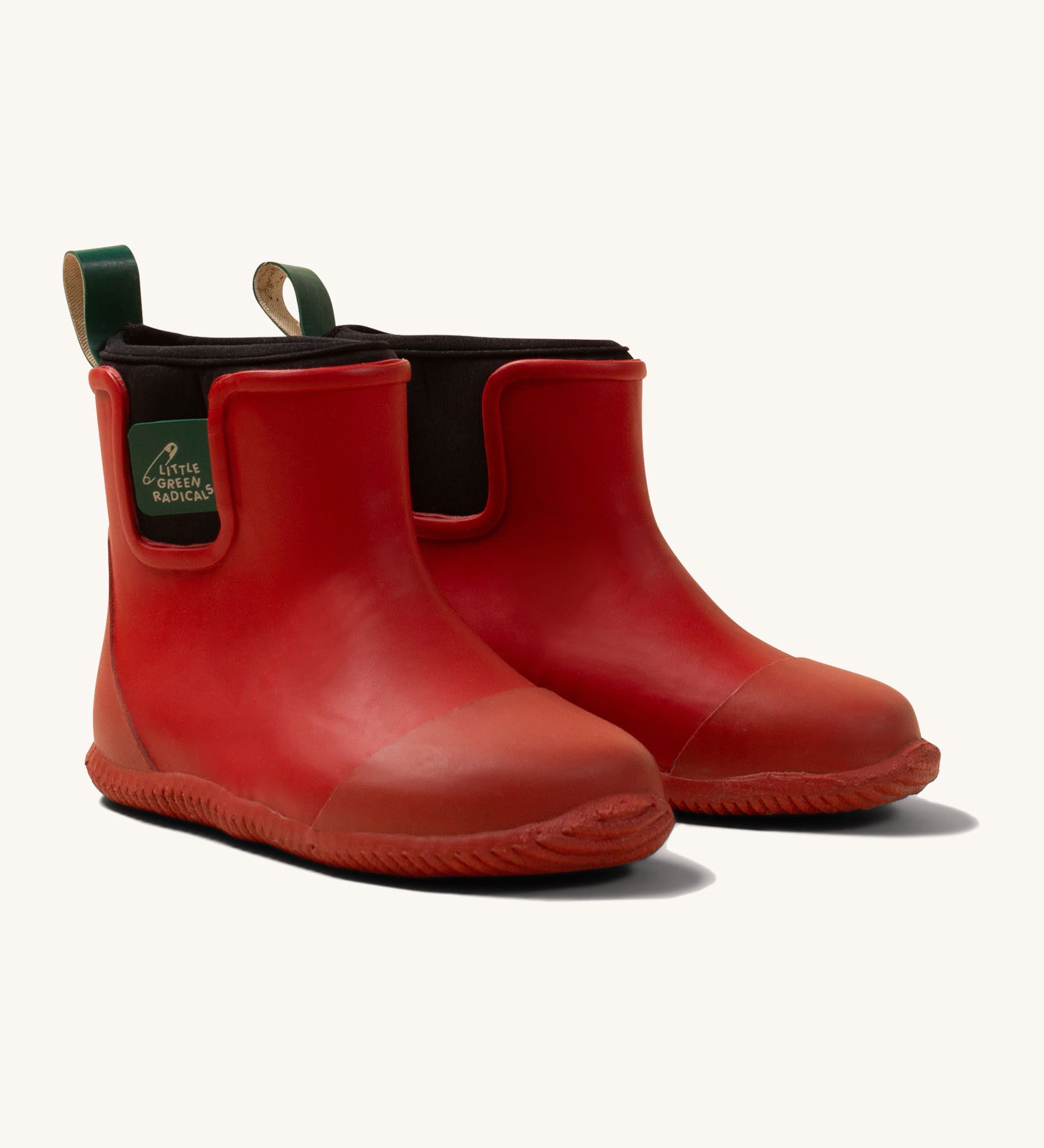 Little Green Radicals ankle wellington boots in red available at Babipur. A natural rubber wellington boot in red with a black elasticated ankle cuff and a green tab on the back.