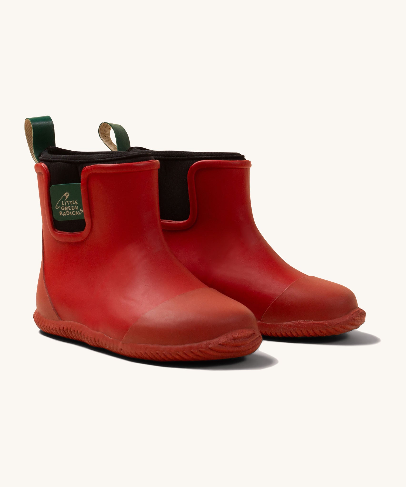 Little Green Radicals ankle wellington boots in red available at Babipur. A natural rubber wellington boot in red with a black elasticated ankle cuff and a green tab on the back.