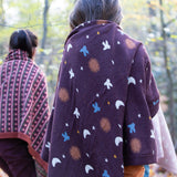 Child in a forest wrapped in a brown flying birds pattern knitted baby blanket by Little Green Radicals - made from Fairtrade and GOTS certified organic cotton, for sale at Babipur.