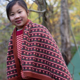 A knitted baby blanket with a brown and retro red floral pattern by Little Green Radicals — made from Fairtrade and GOTS-certified organic cotton — keeps a child cosy in the forest, available at Babipur.