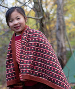 A knitted baby blanket with a brown and retro red floral pattern by Little Green Radicals — made from Fairtrade and GOTS-certified organic cotton — keeps a child cosy in the forest, available at Babipur.