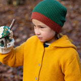 Close up of a child in a forest wearing a knitted beanie hat in chive green with a crimson made from soft Fairtrade and GOTS certified organic cotton by Little Green Radicals - for sale at Babipur.