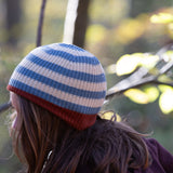 Side of child's head wearing a blue and cream striped knitted beanie with a red trim by Little Green Radicals - made with Fairtrade certified and GOTS organic cotton - available now at Babipur.
