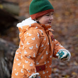 Child running through a forest wearing a chive green with a crimson trim Knit Beanie by Little Green Radicals with a red trim and matching scarf - made from soft GOTS organic and Fairtrade certified cotton - for sale at Babipur.