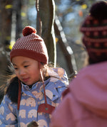 Close up of child wearing a Fairtrade orange and cream diamond patterned organic cotton knit pom pom hat, by Little Green Radicals, for sale at Babipur.