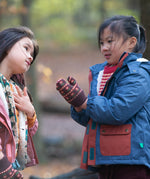 Child playing in a forest wearing a Long Sleeve Orange Ginger Knit Mittens by Little Green Radicals - made from soft GOTS organic and Fairtrade certified cotton - brown with red flowers, available to buy at Babipur.