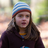 Close up of a child wearing a knitted beanie hat in cream and blue stripes made from soft Fairtrade and GOTS certified organic cotton by Little Green Radicals - for sale at Babipur.