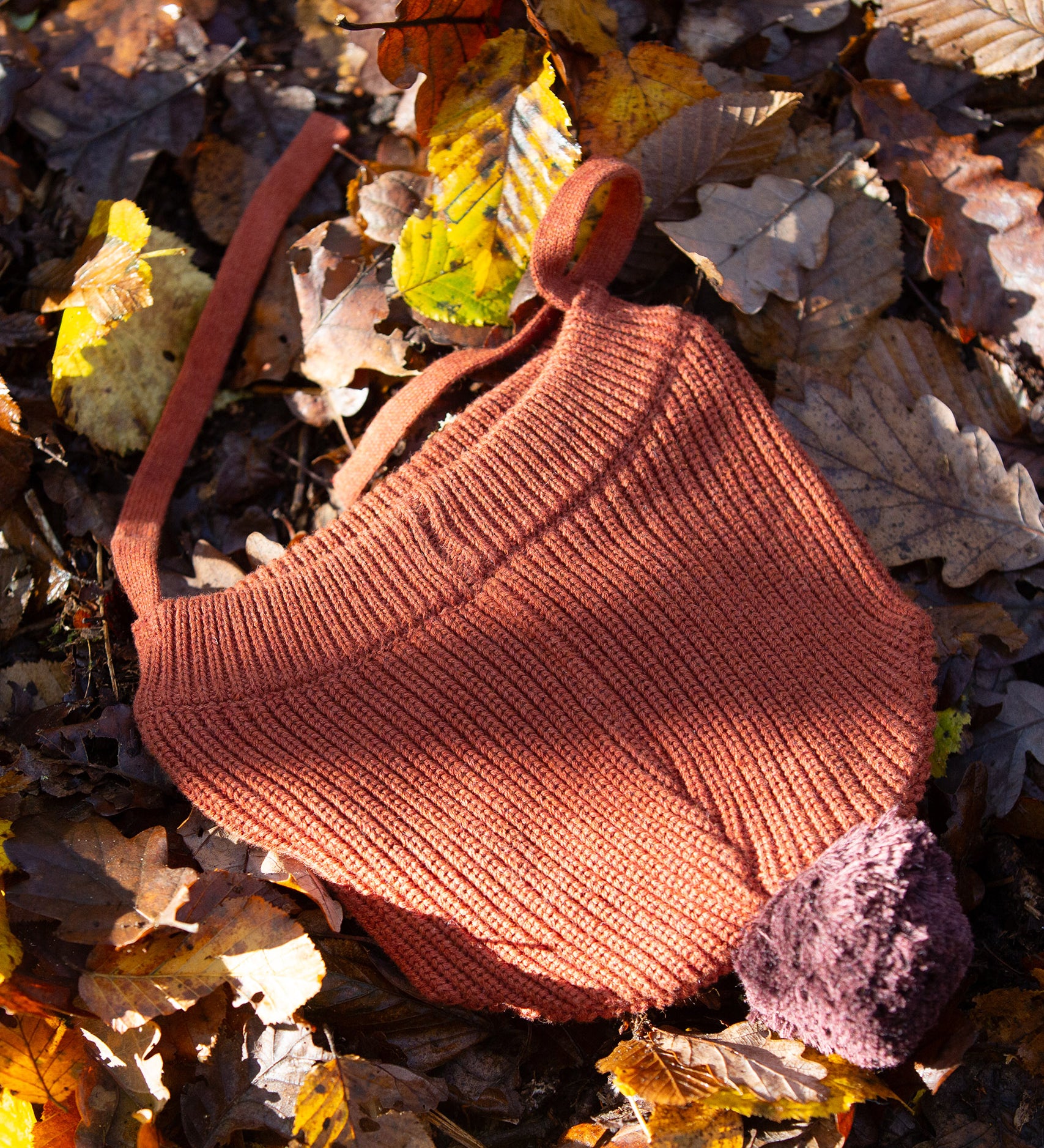 Little Green Radicals Knitted Ginger Orange Kids Hat with a brown pom pom and chin straps, made from soft and warm Fairtrade and organic cotton - for sale at Babipur.