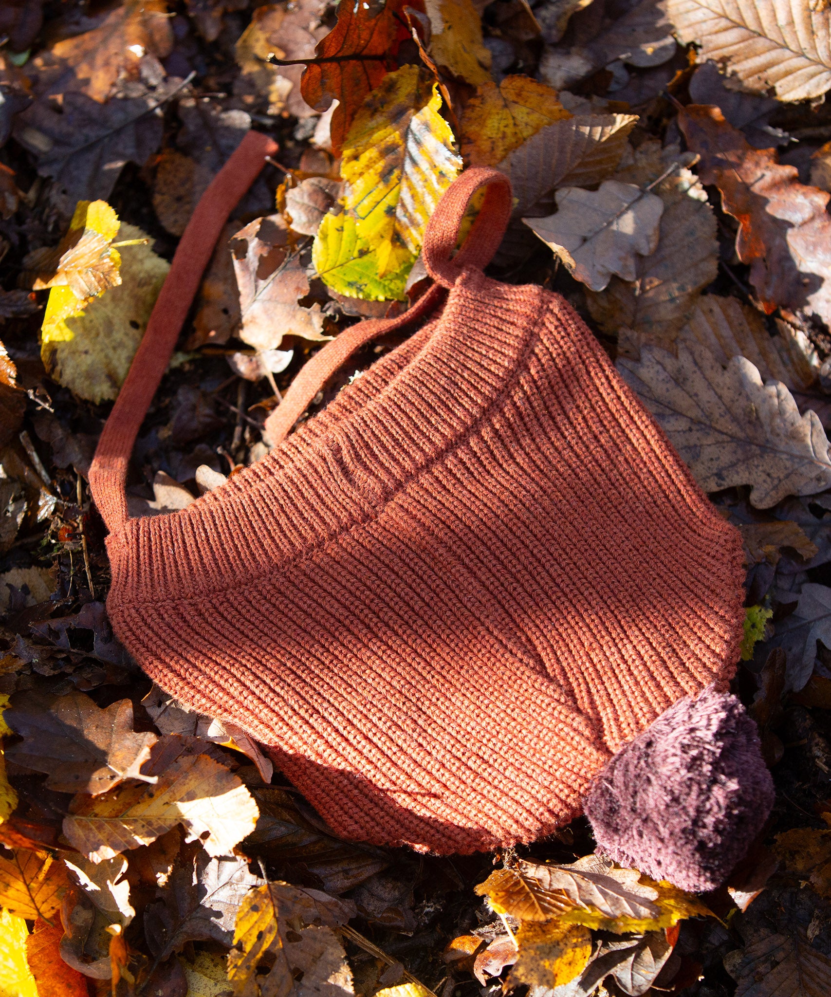 Little Green Radicals Knitted Ginger Orange Kids Hat with a brown pom pom and chin straps, made from soft and warm Fairtrade and organic cotton - for sale at Babipur.