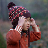 Close up of child in a forest wearing Little Green Radicals Long-Sleeve Knitted Collar Dress in Ginger Orange - made from soft Fairtrade certified and GOTS organic cotton - with striped cream and orange cuffs and three wooden buttons - available to buy at Babipur.