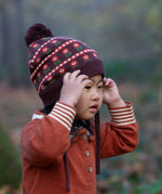 Close up of child in a forest wearing Little Green Radicals Long-Sleeve Knitted Collar Dress in Ginger Orange - made from soft Fairtrade certified and GOTS organic cotton - with striped cream and orange cuffs and three wooden buttons - available to buy at Babipur.