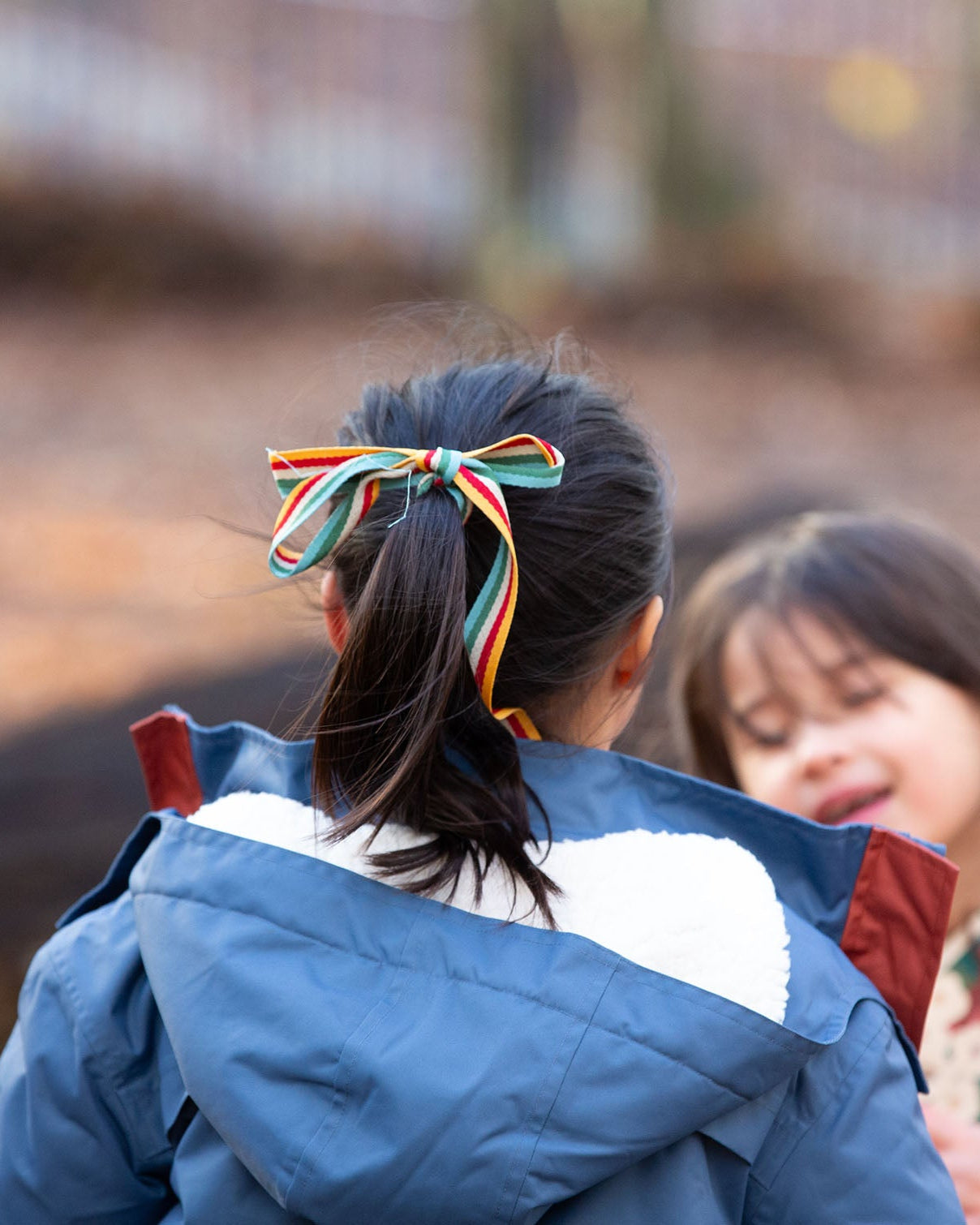 Close up of the back of a child outdoor wearing a Kids Warm Waterproof, 5000MM rating, PFC Free, Winter Hooded School Coat in Moonlight Blue print, with a cosy and fluffy lined hood, by Little Green Radicals, made from recycled bottles and a cosy polyester fleece, buy now at Babipur.
