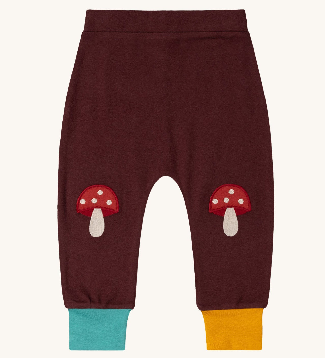 Little Green Radicals knee patch joggers in toadstool design available at Babipur. A GOTS organic cotton jogger in dark maroon with blue and yellow leg cuffs. Features toadstool applique kneepatches 
