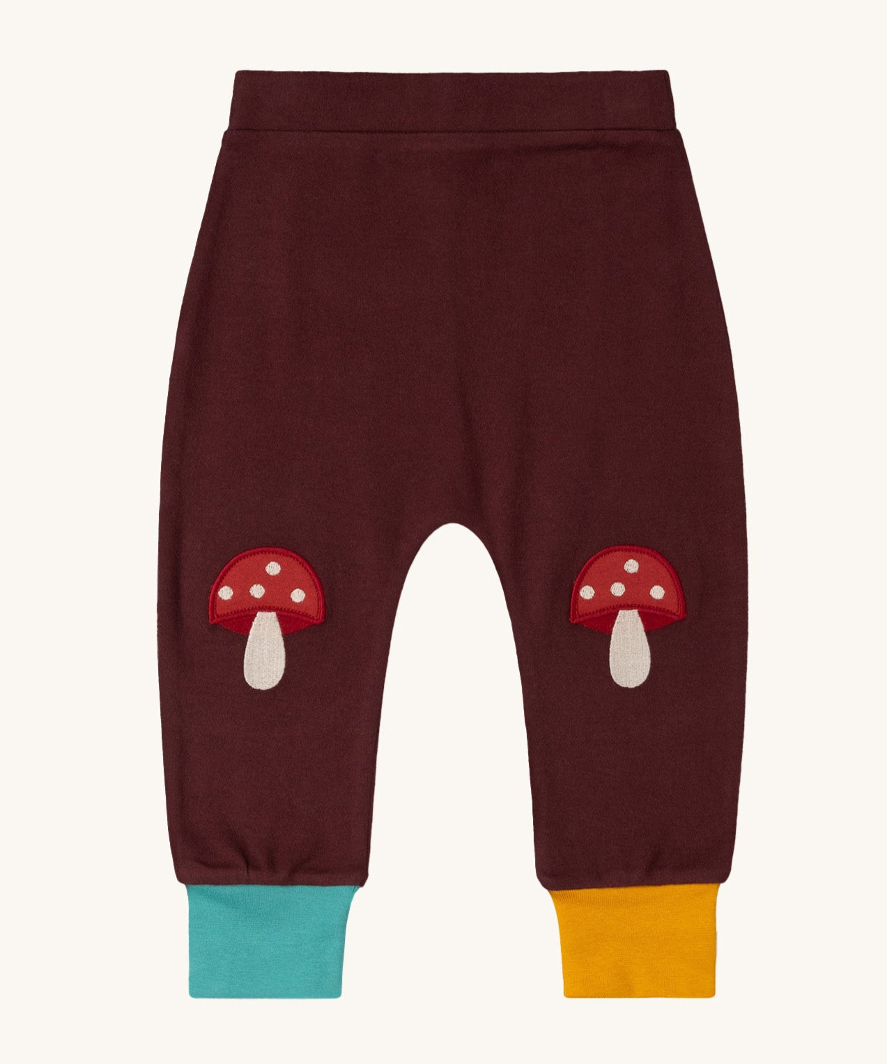 Little Green Radicals knee patch joggers in toadstool design available at Babipur. A GOTS organic cotton jogger in dark maroon with blue and yellow leg cuffs. Features toadstool applique kneepatches 