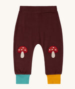 Little Green Radicals knee patch joggers in toadstool design available at Babipur. A GOTS organic cotton jogger in dark maroon with blue and yellow leg cuffs. Features toadstool applique kneepatches 