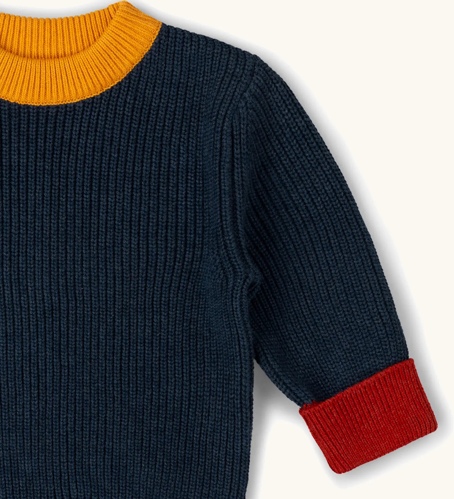 Little Green Radicals Knitted Snuggly Jumper in Midnight Blue, a chunky knit, made from Fairtrade cotton with a yellow collar and red cuffs.
