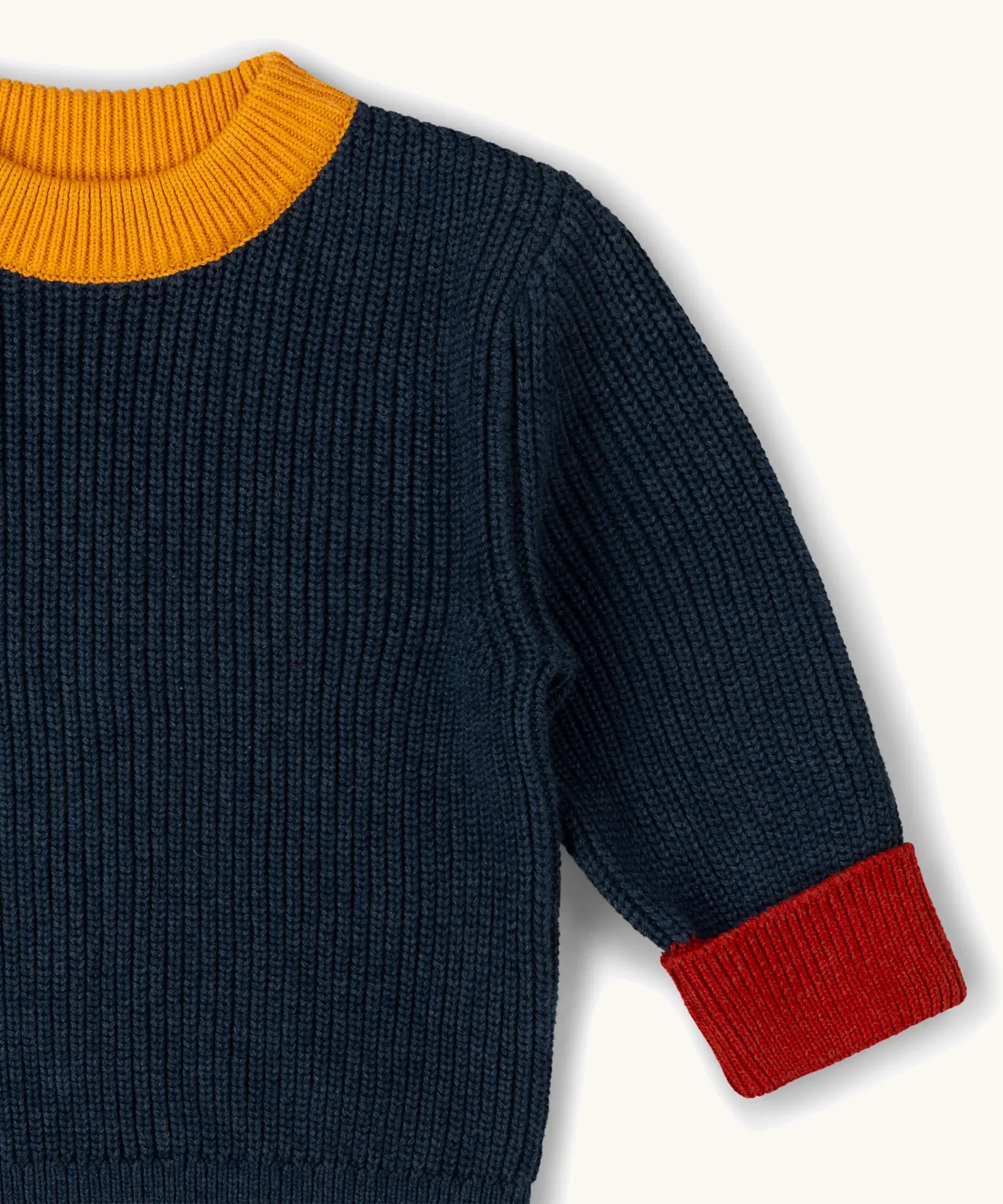 Little Green Radicals Knitted Snuggly Jumper in Midnight Blue, a chunky knit, made from Fairtrade cotton with a yellow collar and red cuffs.