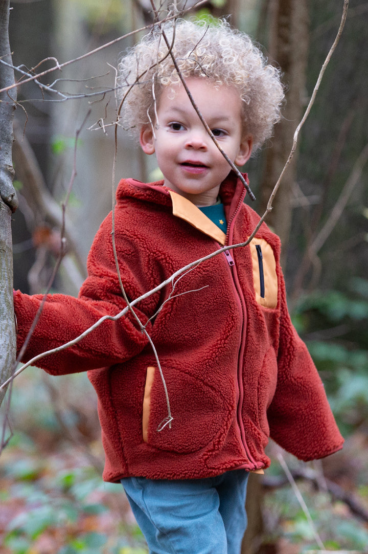 Child wearing Little Green Radicals Cosy Fleece Jacket in Ginger Red - made from recycled fleece - to represent new Autumn Winter 2025  Little Green Radicals at Babipur.