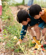 Little Green Radicals Raglan Sweatshirt in blue Midnight Moon print with yellow cuffs on a child gardening. 