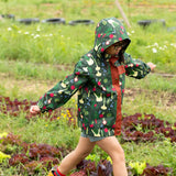 Child wearing the Little Green Radicals feast waterproof recycled kids raincoat with blue pinstripe shorts underneath with yellow wellington boots. 
