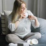 A person putting on the Lola & Lykke Curved Bamboo Nursing Pads, under their top