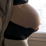 A person with their hand on their pregnancy bump, wearing the Lola & Lykke Core Relief Pregnancy Support Belt