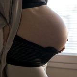 A person with their hand on their pregnancy bump, wearing the Lola & Lykke Core Relief Pregnancy Support Belt