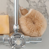 LoofCo sisal shower puff brush resting on a shower tap next to a soap bar