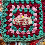 A close up of the Oshana patch on the MADE51 Habibi Small Handmade Crochet Blanket
