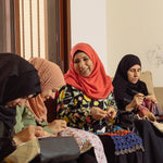 Syrian Refugees sitting together hand-making beautiful blankets, pouches and bags